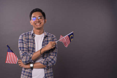 Happy Malaysian teenager holding Malaysia Flag.Independence day and patriotic concept.Studio Shot.の写真素材