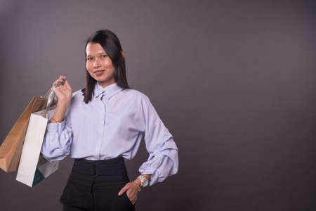 Asian woman with office attire holding shopping bags.の写真素材