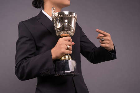 A young business man holding a gold trophy and celebrate his achievement. Close up shotの写真素材