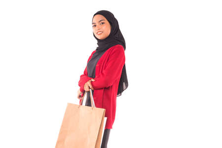 Happy young Muslim girl holding shopping bags isolated over white background.の写真素材