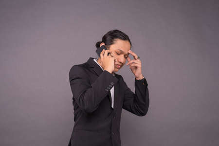 Stressed business man while answering phone.の写真素材