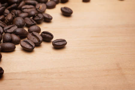 Close up shot of coffee beans on wooden vintage chopping board with copy space.