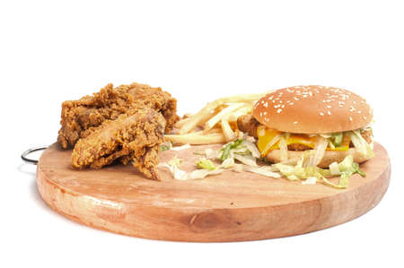 Fried chickens,cheese burger with fries on wooden chopping board isolated over white background.の写真素材