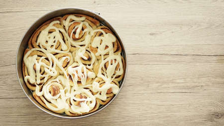 Top view of hot cinnamon rolls in the tray on the wooden kitchen table with copy space.の写真素材