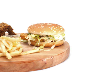Fried chickens,cheese burger with fries on wooden chopping board isolated over white background.の写真素材