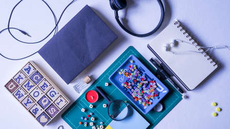 Notebook, magnifying glass and few other stationery objects on white table.View from top.Education...