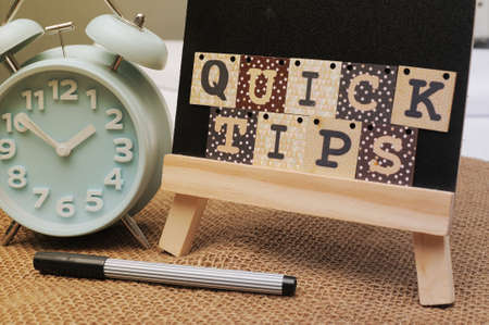 Chalk board and analog alarm clock with text Quick Tips written on the board.