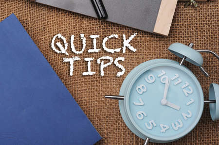 Chalk board and analog alarm clock with text "Quick Tips" written on the board.の写真素材