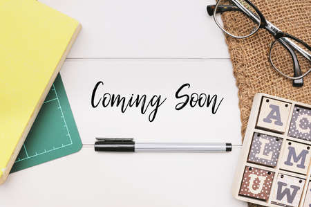 Books,pen and coins on white table written with text "Coming Soon".の写真素材
