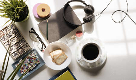 Top view of breakfast menu on white dining table.Coffee,milk, cereal, apple,cracker and bun on white table view from top.Food lay flat concept.の写真素材