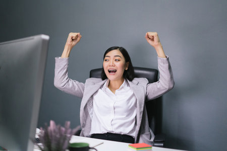 Happy female worker at her office desk and smiling.の写真素材