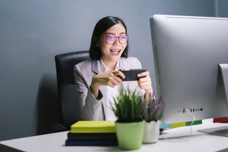 Happy female worker at her office desk holding cup and smiling.の写真素材