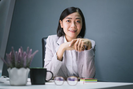 Happy female worker at her office desk and smiling.の写真素材