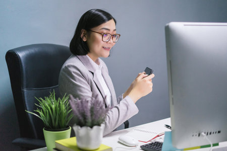 Happy female worker at her office desk and smiling.の写真素材