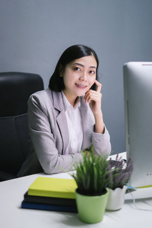 Happy female worker at her office desk and smiling.の写真素材