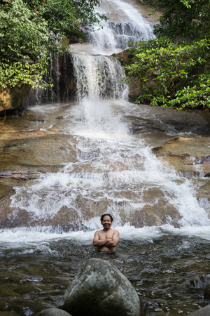22nd September 2020,Shah Alam Selangor.A teenager in the waterfall pool.Male hiker enjoying the view of rain forest waterfall.のeditorial素材