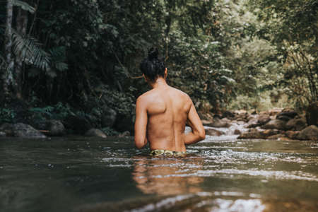 A male traveler in the rain forest pool stream or waterfall.Healthy and active lifestyle.Camping and hiking.の写真素材