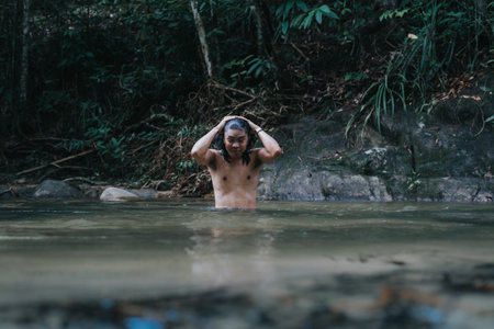 A male traveler in the rain forest pool stream or waterfall.View from behind.Healthy and active lifestyle.Camping and hiking.の写真素材