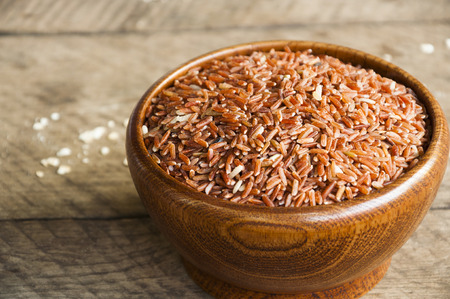 Brown rice in wood cup have wood table is backgruond.の写真素材
