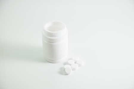 Prescription pill bottle spilling pills on to surface on a white background.の写真素材