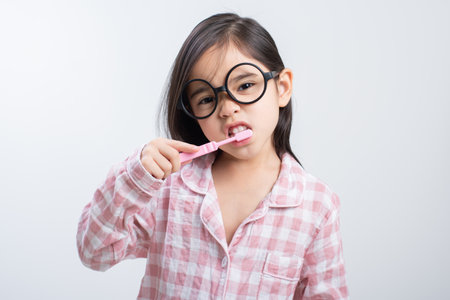 little girl Asia brushing teeth happily white backgroundの写真素材