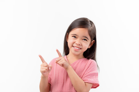 Portrait Of Cute Girl asia With Long Hair Gesturing pointing finger While Standing Against White Backgroundの写真素材