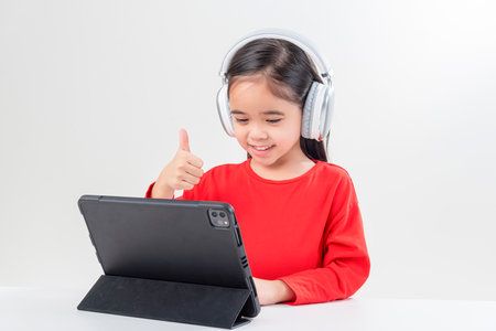 little girl asia cute put on headphones have video call distant class with teacher using laptop,  study online on computer, homeschooling conceptの写真素材