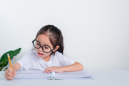 Portrait of little pupil writing at desk in  Student girl study doing test in primary school....