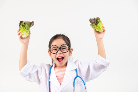Asia little girl playing doctor recommends vegetables and fruits for proper nutrition and benefits to your health isolated on whiteの写真素材