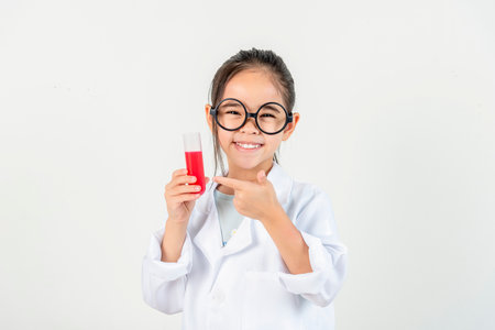 education, science and children concept girl in goggles with magnifier studying test tube with chemical at home laboratoryの写真素材