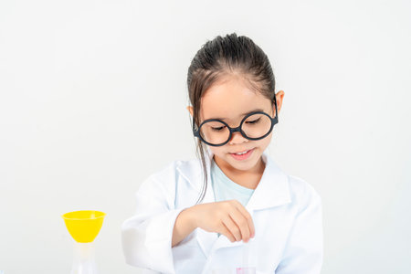 education, science and children concept girl in goggles with magnifier studying test tube with chemical at home laboratoryの写真素材