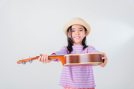 Cute little girl in swimsuit playing ukulele. Happy vacation concept.の写真素材