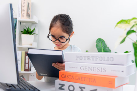 little asian girl studying at home with books in front of computerの写真素材