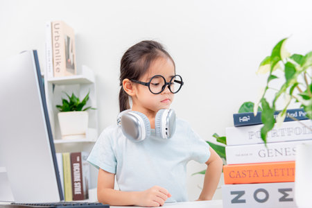 cute little asian girl wearing eyeglasses using computer at home