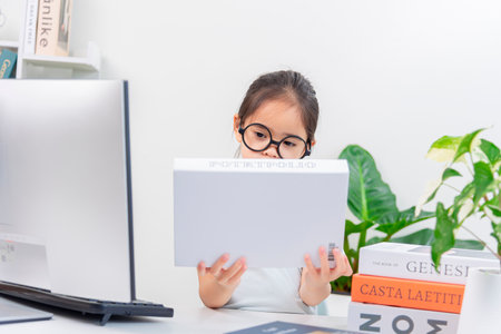 little asian girl in eyeglasses using digital tablet at homeの写真素材