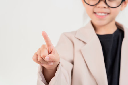 Little business lady Asia. Cute little girl in glasses and formalwear pointing at the front standing on a white backgroundの写真素材