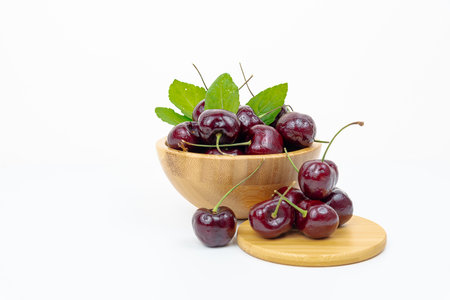 Background Fresh fruit red sweet cherrys isolated in a wooden cup on white backgroundの写真素材