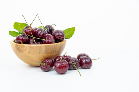 Background Fresh fruit red sweet cherrys isolated in a wooden cup on white backgroundの写真素材