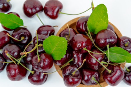 Background Fresh fruit red sweet cherrys isolated in a wooden cup on white backgroundの写真素材