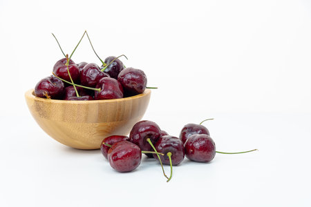 Background Fresh fruit red sweet cherrys isolated in a wooden cup on white backgroundの写真素材