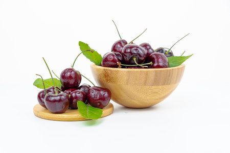 Background Fresh fruit red sweet cherrys isolated in a wooden cup on white backgroundの写真素材