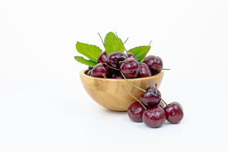 Background Fresh fruit red sweet cherrys isolated in a wooden cup on white backgroundの写真素材