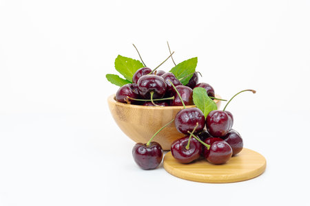 Background Fresh fruit red sweet cherrys isolated in a wooden cup on white backgroundの写真素材