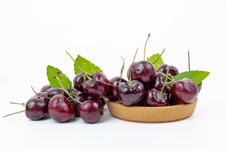 Background Fresh fruit red sweet cherrys isolated in a wooden cup on white backgroundの写真素材