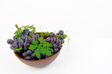 fresh fruit Purple grape Kyoho Grape with leaves in a wooden cup isolated on white background