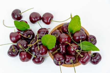Background Fresh fruit red sweet cherrys isolated in a wooden cup on white backgroundの写真素材