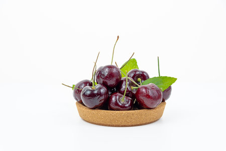 Background Fresh fruit red sweet cherrys isolated in a wooden cup on white backgroundの写真素材