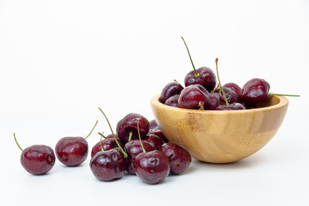 Background Fresh fruit red sweet cherrys isolated in a wooden cup on white backgroundの写真素材