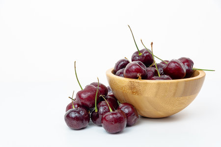 Background Fresh fruit red sweet cherrys isolated in a wooden cup on white backgroundの写真素材