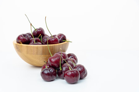Background Fresh fruit red sweet cherrys isolated in a wooden cup on white backgroundの写真素材